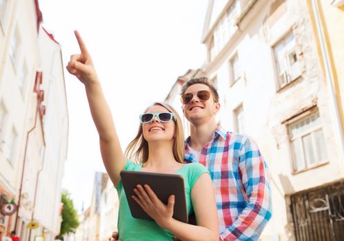 travel, vacation, technology and friendship concept - smiling couple with tablet pc computer in city