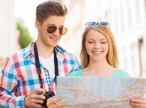 travel, vacation, technology and friendship concept - smiling couple with map and photo camera exploring city