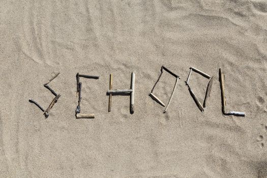 A set of sticks forming the word school in a sandy beach use it for background
