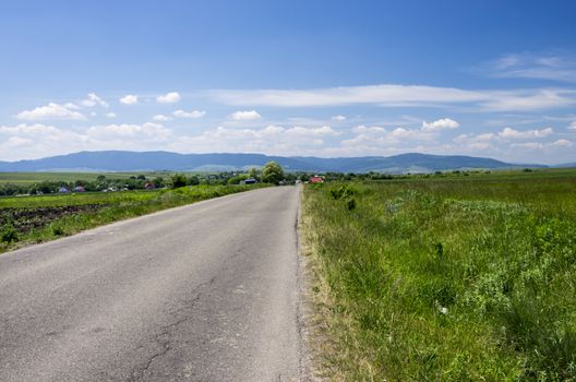 Road on meadow and mountain panorama
