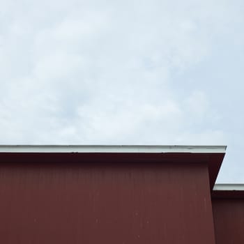 Side of a red building with contrasting roof edge against an overcast sky 