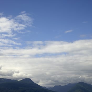 Tops of tree covered mountains agaisnt a cloudy sky