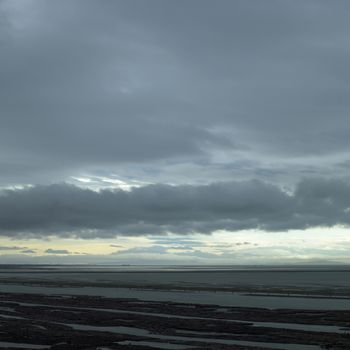 Dark stormy sky over log covered ocean