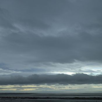 Dark stormy sky over log covered ocean