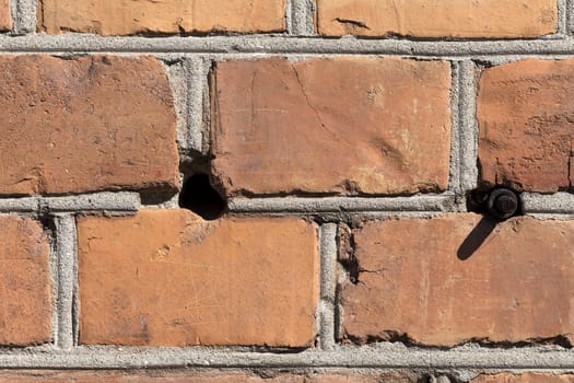 A detailed photo of a brick wall with all the damaged parts and the plaster. This one also have a hole and a bolt sticking out