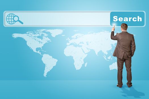 Businessman standing and pressing on browser on abstract blue background with world map, rear view