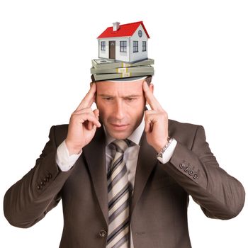 Thoughtful businessman looking down with money and house in his head on isolated white background