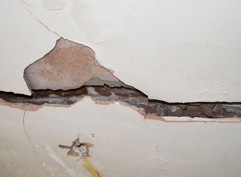 badly cracked plasterboard on interior wall showing bricks behind