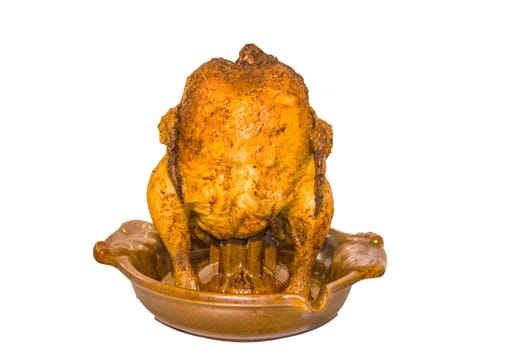 Close up of a brown fried chicken on a barbecue grill poultry holder against white background.