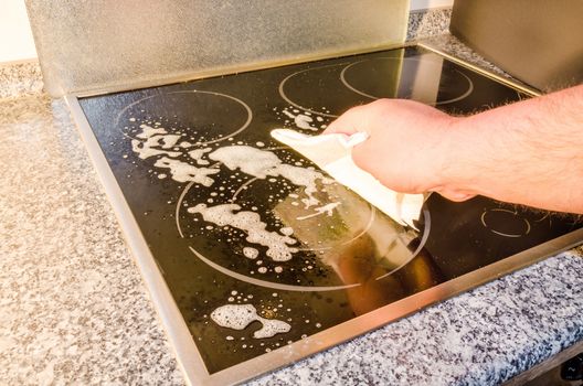 Ceramic hob, induction hob cleaning. Stove with detergent and cleaning cloth.