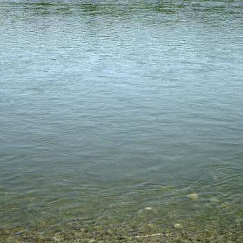 Calm green waters of a natual body exposing rocks and stones