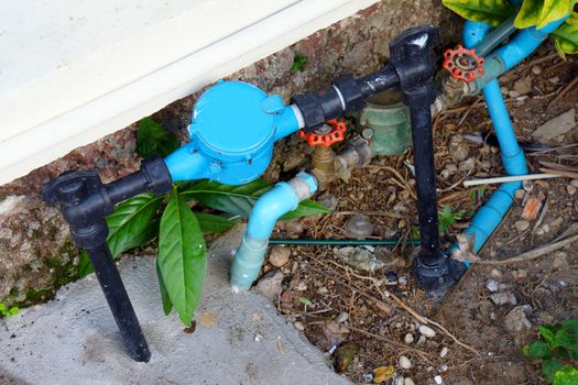 Old and dirty tab water pipe and meter with waterspout on ground floor.