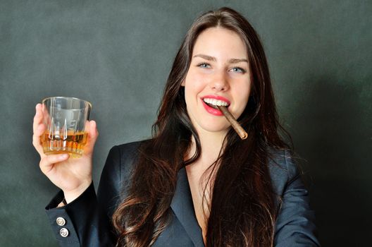 Young girl holding cigar and glass of whisky. Happy face expression, party style.