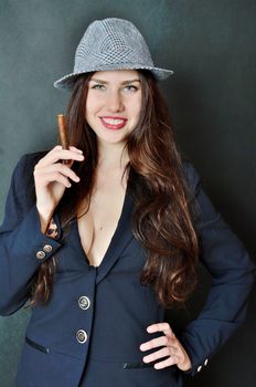 Girl with tail-coat and hat. Female model holding cigar, confident brunette.