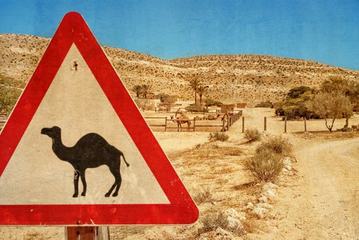 Road sign - camel and corral for camels. Negev desert. Photo textured in old color image style.