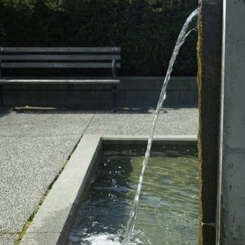 Water spout pours into an urban water feature