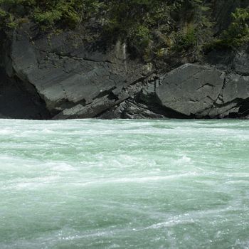 Green river water flowing near rocky edges