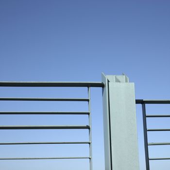 Gray steel welded metal of an industrial railing against blue sky