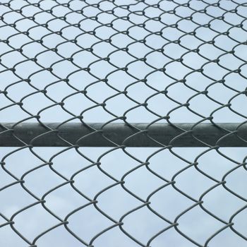 Steel pole and chain links of a metal fence 