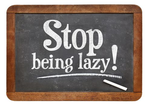 Stop being lazy sign - white chalk text on a vintage slate blackboard