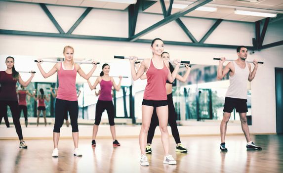 fitness, sport, training, gym and lifestyle concept - group of smiling people working out with barbells in the gym