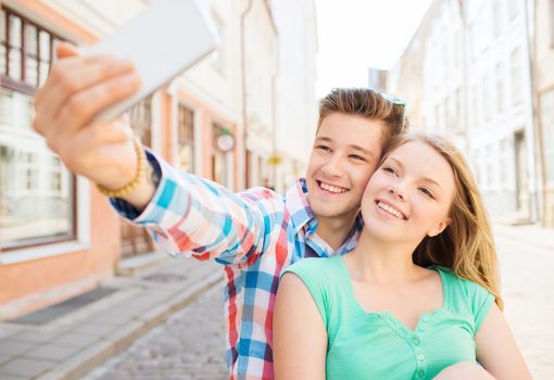 travel, vacation, technology and friendship concept - smiling couple with smartphone in city