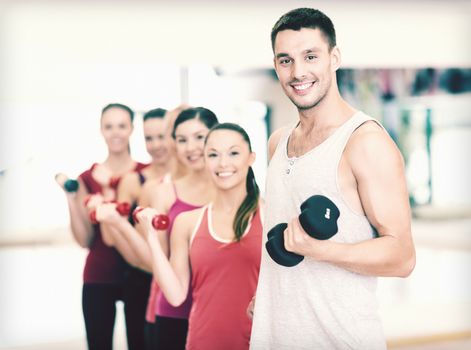 fitness, sport, training, gym and lifestyle concept - group of smiling people lifting dumbbells in the gym