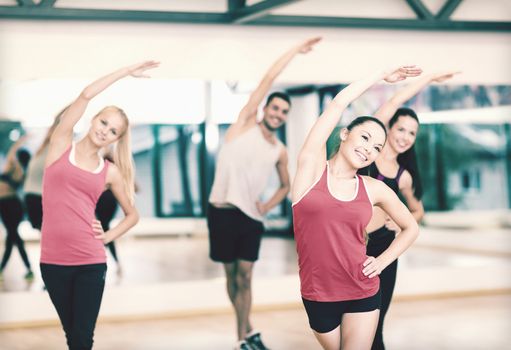 fitness, sport, training, gym and lifestyle concept - group of smiling people stretching in the gym