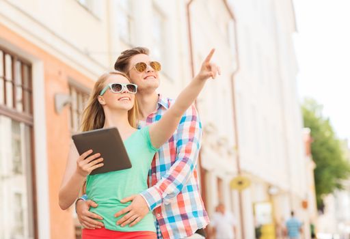 travel, vacation, technology and friendship concept - smiling couple with tablet pc computer in city