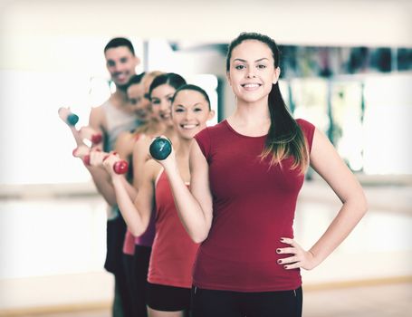 fitness, sport, training, gym and lifestyle concept - group of smiling people lifting dumbbells in the gym