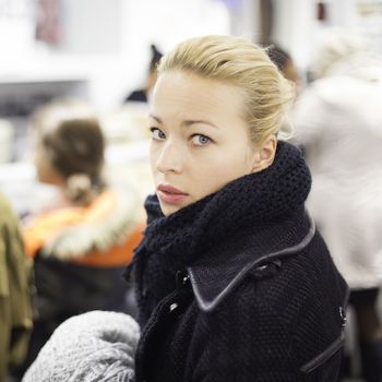 Woman shopping clothes. Shopper queuing in line at cashier in textile store. Beautiful blonde caucasian female model. 