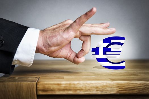 Business Man shoots with his finger off the Euro sign with greek flag of a table