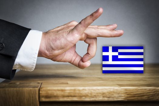 Business Man shoots with his finger off the Greek flag of a table