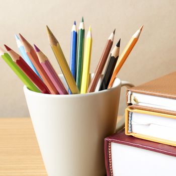 stack of book with color pencil on wood table background