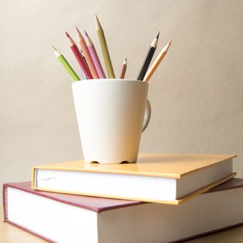 stack of book with color pencil on wood table background