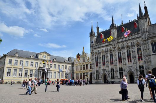 Bruges, Belgium - May 11, 2015: Tourists on Burg square with City Hall in Bruges, Belgium on May 11, 2015. The historic city centre is a prominent World Heritage Site of UNESCO.