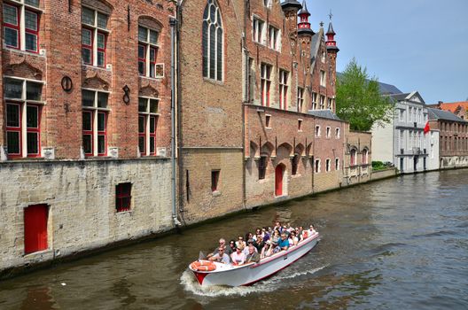 Bruges, Belgium - May 11, 2015: Tourists in canal boats in Bruges, Belgium. Bruges is the capital and largest city of the province of West Flanders in the Flemish Region of Belgium. 