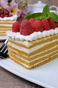 Piece of honey cake with whipped cream and raspberries