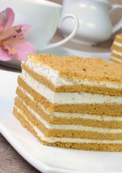 Piece of honey cake with a cup of coffee on a table with a flower