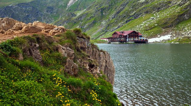 BALEA LAKE, ROMANIA - JUNE 24, 2012: Idyllic view with cottege on Balea Lake shore in Fagaras Mountains, Romania.