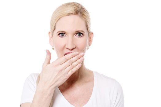 Shocked middle aged woman with hand over mouth