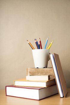 stack of book with color pencil on wood table background