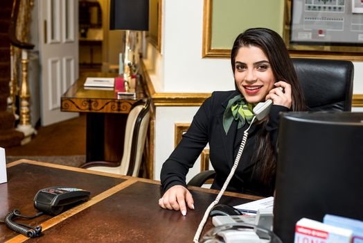 Smiling stylish receptionist talking on telephone