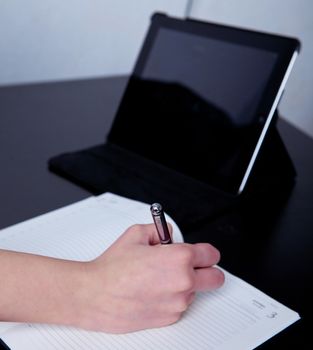 business woman in a cafe making notes in a diary, on the background of the phone and tablet