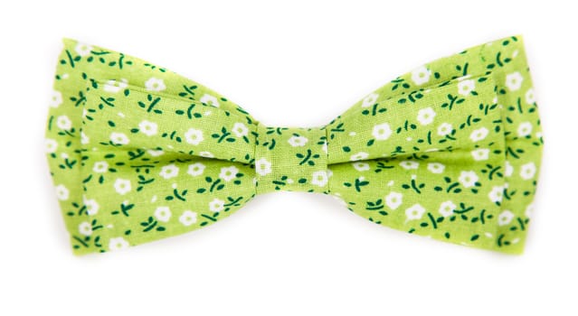 green bow tie with a pattern with summer flowers on an isolated white background