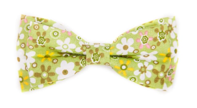 green bow tie with a pattern with summer flowers on an isolated white background