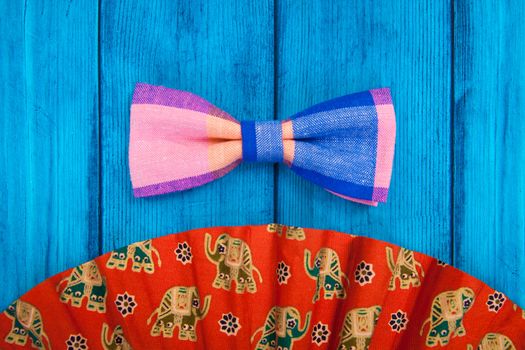 fan with red bow tie on blue wooden background