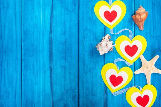 red hearts on a colored rope and starfish on blue wooden background