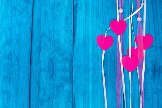 red hearts on a colored rope on blue wooden background