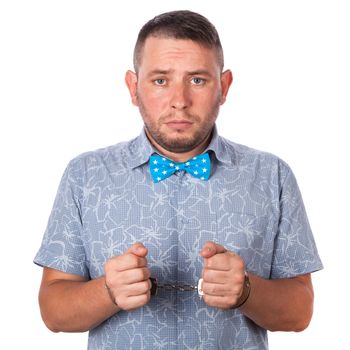 Adult male with beard in a blue bow tie in summer shirt in police handcuffs isolated on a white background